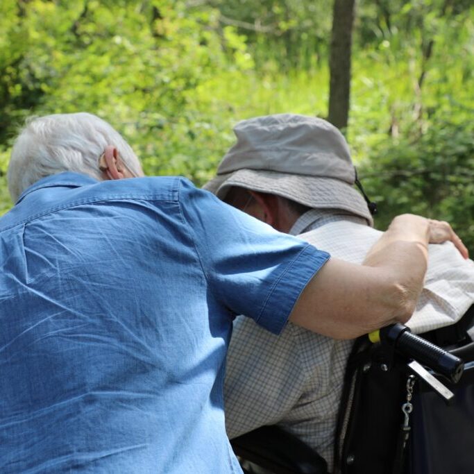 elderly couple with arms around one another