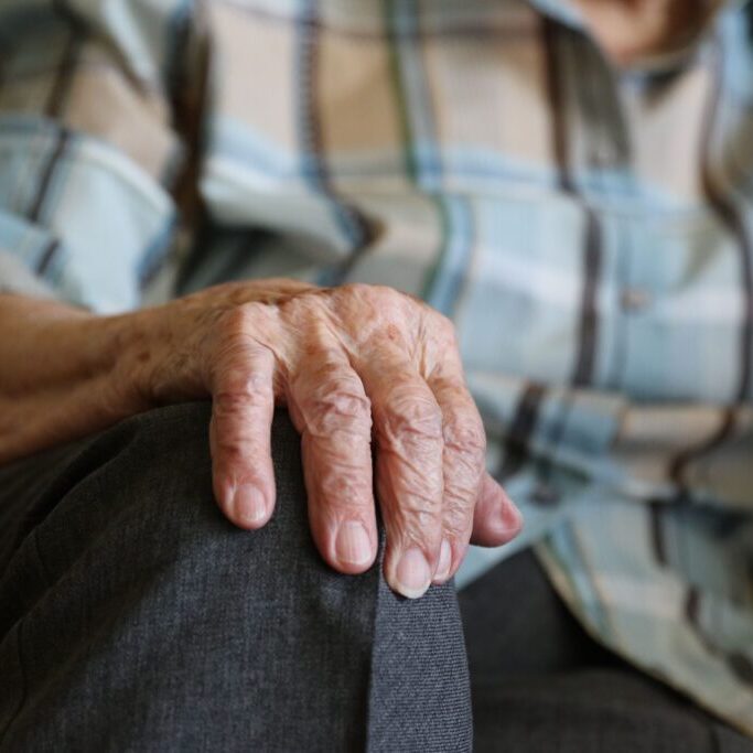 closeup with old woman's hand on her knee